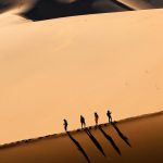 Diferencia entre turismo y viaje en un paisaje desértico con figuras humanas